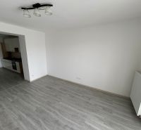 Wohnzimmer einer 3-Zimmer-Wohnung mit Holzboden und Küche auf der linken Seite.