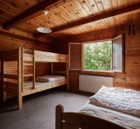Ein Schlafzimmer in einer Hütte mit einem Etagenbett, Holzverkleidung und offenem Fenster.