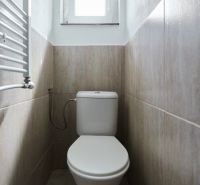 Badezimmer in der Hütte mit Toilette und Fliesen in hellen Farbtönen.
