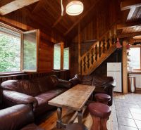 Innenraum einer Hütte mit Ledersofas, Kamin und Holzboden.