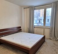Schlafzimmer mit grauen Vorhängen, großem Fenster und Bett in einer 2-Zimmer-Wohnung.