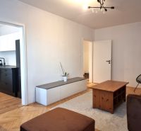 Wohnzimmer in einer 2-Zimmer-Wohnung mit Holzboden, mit Blick in die Küche.