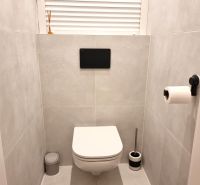 Badezimmer in einer 2-Zimmer-Wohnung mit modernem hängendem WC auf hellen Fliesen.