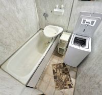 Badezimmer in einer 3-Zimmer-Wohnung mit Badewanne, Waschmaschine und Fliesen.