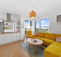 Wohnzimmer einer 4-Zimmer-Wohnung mit Holzboden und gelbem Sofa.