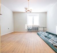 Ein Raum in einem Einfamilienhaus mit einem Holzboden und einem Stapel Stangen am Fenster.