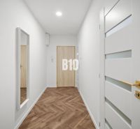 Flur einer 3-Zimmer-Wohnung mit Holzboden und einem Spiegel an der Wand.
