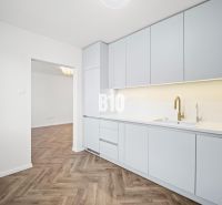 Küche in einer 3-Zimmer-Wohnung mit weißen Möbeln und einem Boden in Holzoptik.