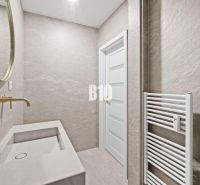 Badezimmer mit goldenem Spiegel und Waschbecken in einer 3-Zimmer-Wohnung, neutrale Töne.