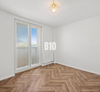 Ein leerer Raum mit Holzboden und Balkontüren in einer 3-Zimmer-Wohnung.