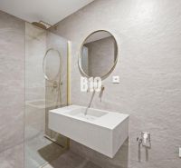 Badezimmer mit rundem Spiegel und Duschkabine in einer 3-Zimmer-Wohnung.