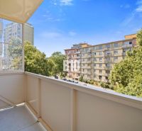 Blick vom Balkon einer Dreizimmerwohnung in Nitra auf die Siedlung und die Bäume.
