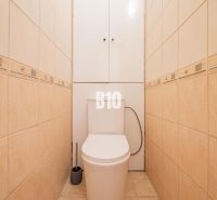 Toilette mit beigefarbenen Fliesen in einer Einzimmerwohnung, praktisches Design und Stauraum.
