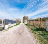 Weg zwischen Wohnbaugrundstücken in Nitra, zwischen dem Zaun und der grünen Vegetation.