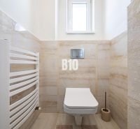 Das Badezimmer in einem Einfamilienhaus enthält ein hängendes WC, Fliesen und einen Heizkörper.