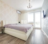 Schlafzimmer mit Bett, gemusterten Tapeten und Holzboden in einem Einfamilienhaus.