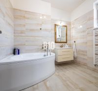 Luxuriöses Badezimmer mit Badewanne und Waschbecken in einem Einfamilienhaus, Boden mit Holzdekor.