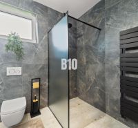 Badezimmer in einem Einfamilienhaus mit einem schwarzen Heizkörper und einer Duschkabine.