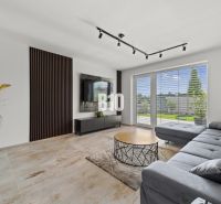 Wohnzimmer in einem Einfamilienhaus mit Sofa, Fernseher und Fenster mit Ausblick.