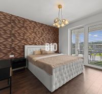 Schlafzimmer mit Holzboden, gestepptem Betthaupt und Blick auf die Terrasse.