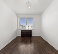 Ein Zimmer in einem Einfamilienhaus mit einem Fenster, einer Kommode und einem Boden in Holzoptik.