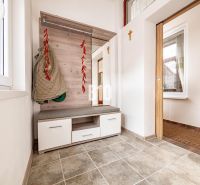 Eingangshalle in einem Einfamilienhaus mit Garderobe, Sitzgelegenheit und Fliesenboden.