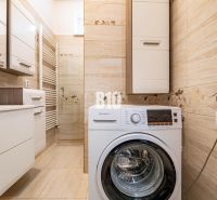 Badezimmer in einem Einfamilienhaus mit Waschmaschine und hellen Fliesen.