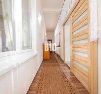 Ein Flur in einem Einfamilienhaus mit einem Boden in Holzoptik und Schiebetüren.