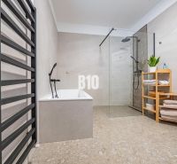 Ein Badezimmer in einem Einfamilienhaus mit Badewanne, Dusche und einem Regal für Handtücher.