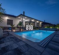 Ein Einfamilienhaus in Nitra mit Pool und Gartenmöbeln in abendlicher Atmosphäre.