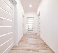 Ein heller Flur in einem Einfamilienhaus mit einem Boden in Holzoptik und weißen Türen.