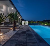 Ein Einfamilienhaus in Nitra mit einem Pool und einem beleuchteten Garten am Abend.