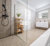 Ein Badezimmer mit einer modernen Dusche und einer Badewanne in einem Einfamilienhaus.