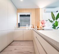 Eine Küche in einem Einfamilienhaus mit Holzboden, weißen Schränken und Blumen.