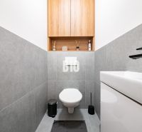Ein Badezimmer in einem Einfamilienhaus mit grauen Fliesen und schlichtem Design.