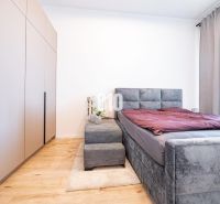 Ein Schlafzimmer in einem Einfamilienhaus mit Bett, Kleiderschrank und einem Boden in Holzoptik.