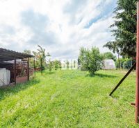 Rasenfläche im Garten eines Einfamilienhauses in Nitra mit Bäumen und einem Schuppen.
