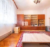 Wohnzimmer mit übersichtlicher Vitrine, Holzboden und rotem Teppich in einem Einfamilienhaus.