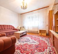 Wohnzimmer in einem Einfamilienhaus mit Sofa, Sessel und Teppich auf einem Boden mit Holzdekor.