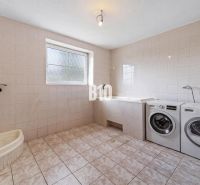 Badezimmer im Einfamilienhaus mit Waschmaschine, Badewanne und Dusche.