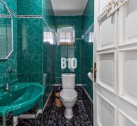 Badezimmer in einem Einfamilienhaus mit grünen Fliesen und Waschbecken.