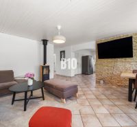 Wohnzimmer in einem Einfamilienhaus mit Kamin und Fernseher an einer mit Stein verkleideten Wand.