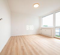 Ein Zimmer in einer 3-Zimmer-Wohnung mit einem Holzboden und großen Fenstern.