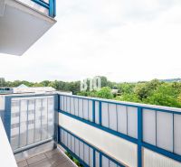 Der Balkon einer 3-Zimmer-Wohnung in Nitra mit Blick auf Grünflächen und Dächer von Gebäuden.