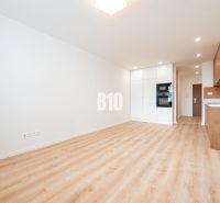 Helle Küche mit weißen Schränken, Holzboden in einer 3-Zimmer-Wohnung.