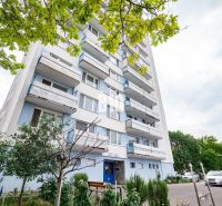 Ein Wohnhaus in Nitra mit Bäumen und einem Parkplatz vor der 3-Zimmer-Wohnung.