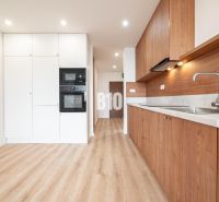 Küche in einer 3-Zimmer-Wohnung mit weißen Schränken und einem Boden in Holzoptik.