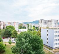 Blick aus einer 3-Zimmer-Wohnung in Nitra auf Plattenbauten und einen Parkplatz mit Autos.