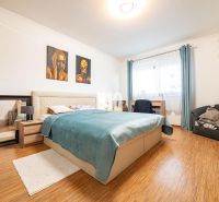 Schlafzimmer im Einfamilienhaus mit Bett, Spiegel und Boden in Holzoptik.
