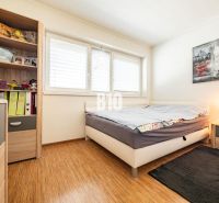 Ein Schlafzimmer in einem Einfamilienhaus mit einem Boden in Holzoptik und einem Regal voller Bücher und Spielzeug.